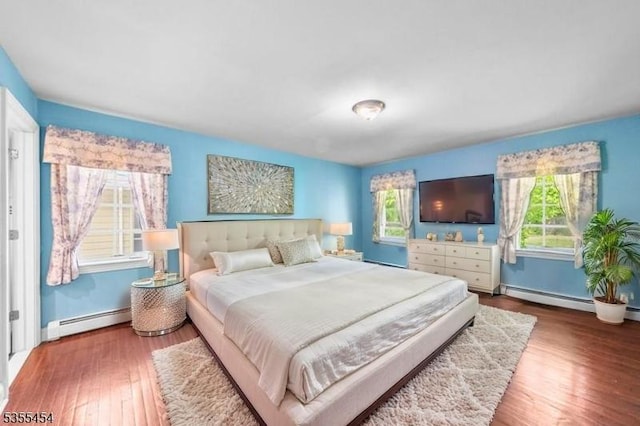 bedroom with baseboards, baseboard heating, and wood finished floors