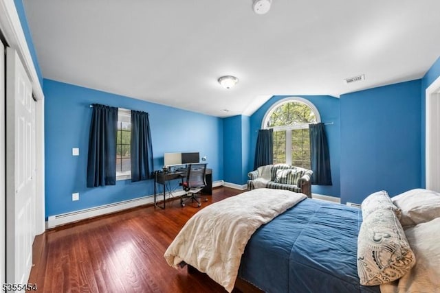 bedroom featuring baseboards, wood finished floors, lofted ceiling, a baseboard radiator, and visible vents