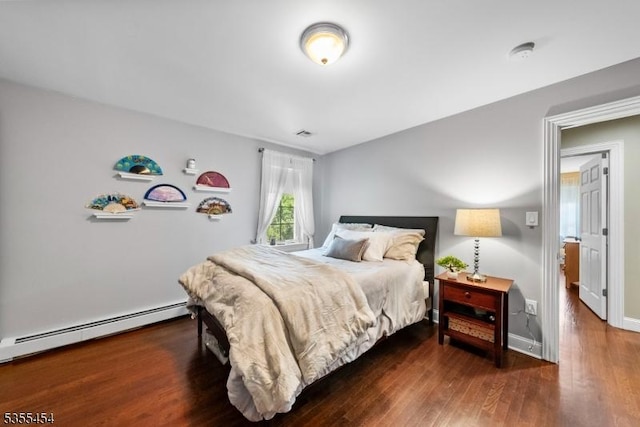 bedroom with baseboards, visible vents, baseboard heating, and wood finished floors