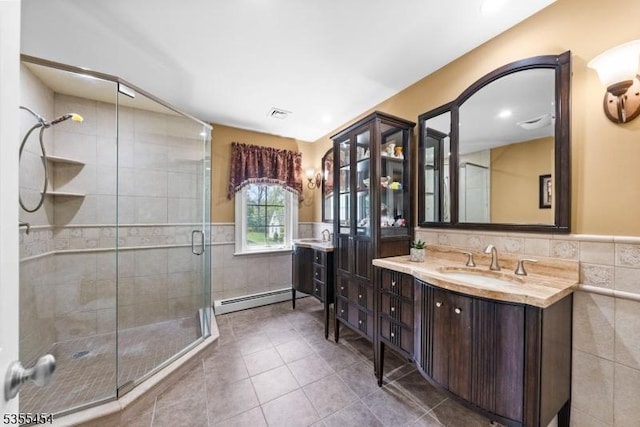 full bath featuring a sink, tile patterned floors, tile walls, a baseboard heating unit, and a stall shower