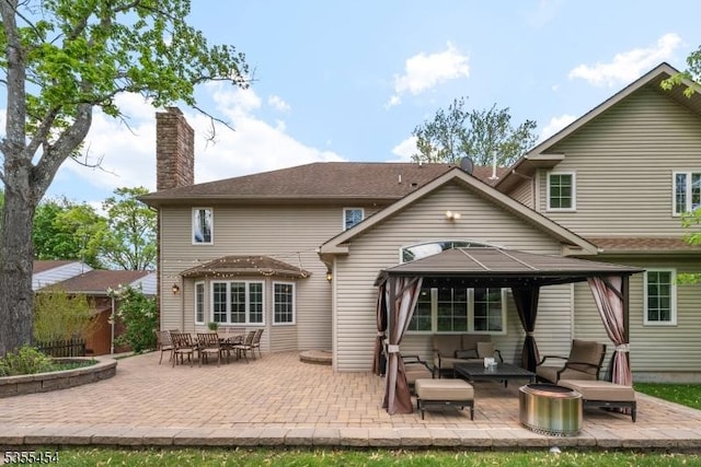 back of property featuring an outdoor hangout area, a gazebo, a chimney, and a patio area