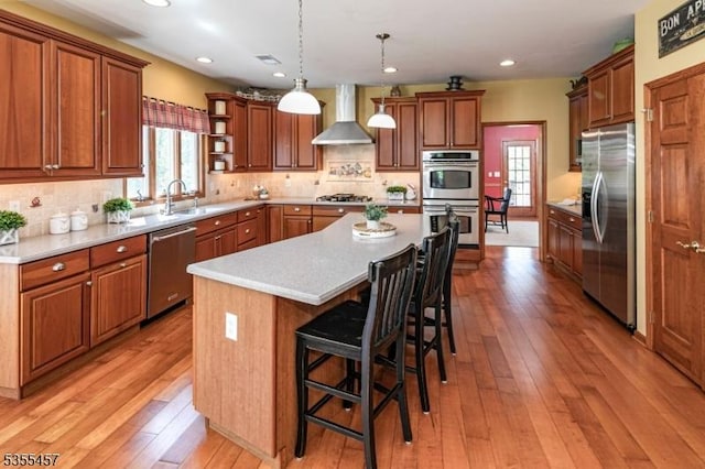 kitchen featuring open shelves, wall chimney range hood, appliances with stainless steel finishes, and light wood-type flooring