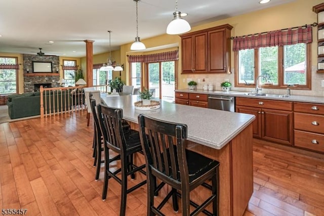 kitchen featuring a stone fireplace, a sink, brown cabinets, light wood-style floors, and light countertops