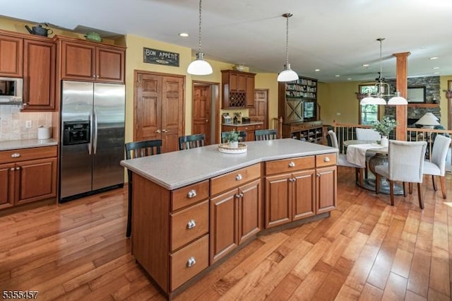 kitchen with pendant lighting, a center island, brown cabinetry, built in fridge, and light countertops