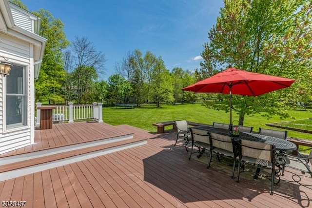 wooden terrace featuring a yard, a trampoline, and outdoor dining area