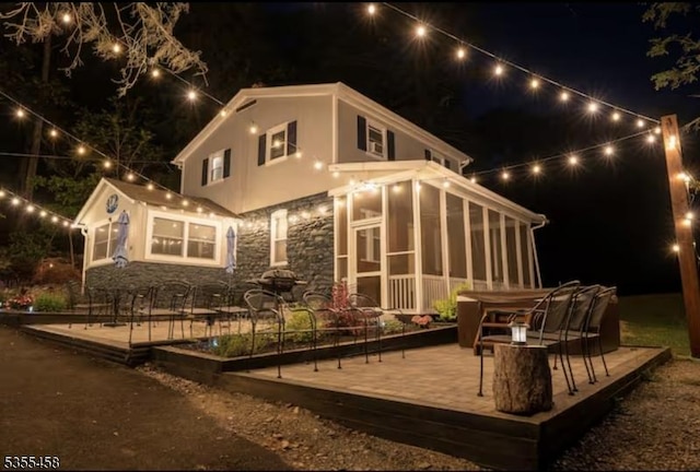 14 Luchetti Way, Andover Twp, NJ 07860 - back of house at twilight featuring a sunroom, a deck, and stone siding