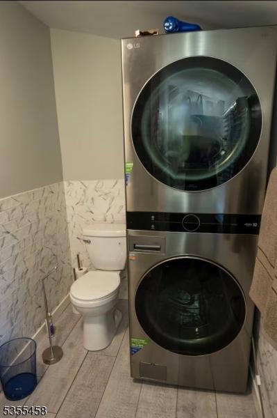 14 Luchetti Way, Andover Twp, NJ 07860 - bathroom featuring toilet, tile walls, wainscoting, and stacked washer and clothes dryer