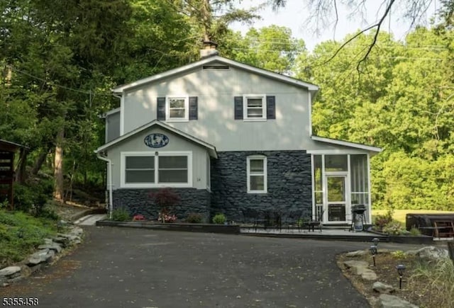 14 Luchetti Way, Andover Twp, NJ 07860 - view of front facade featuring a sunroom, a view of trees, a chimney, and stone siding