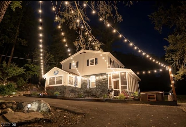 14 Luchetti Way, Andover Twp, NJ 07860 - back of house at twilight featuring a sunroom, stucco siding, and stone siding