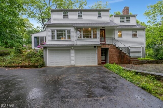 1178 Delaware Dr, Bridgewater Twp, NJ 08807 - view of front of house with an attached garage, asphalt driveway, a chimney, and stairs