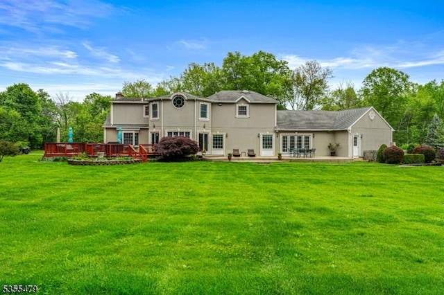 back of property with a deck, a yard, and a patio area