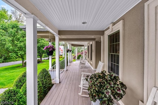 wooden terrace with a porch and a yard