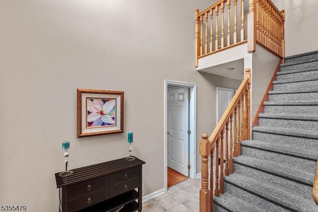 stairway featuring baseboards and a high ceiling
