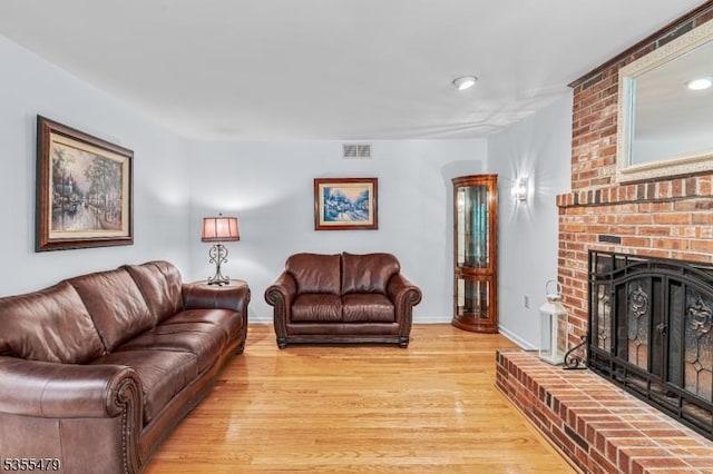 living room with light wood finished floors, a fireplace, and baseboards