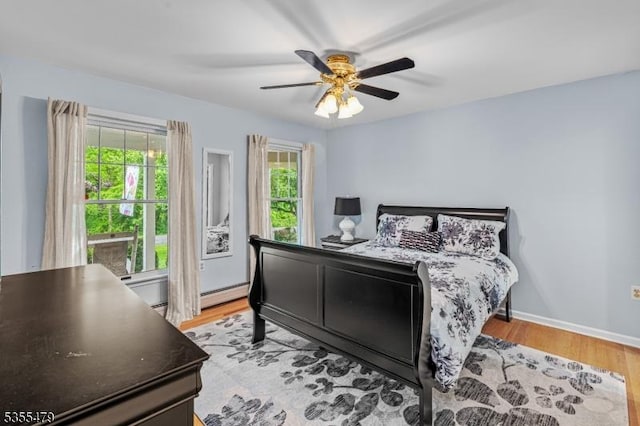 bedroom with a baseboard radiator, light wood finished floors, and ceiling fan