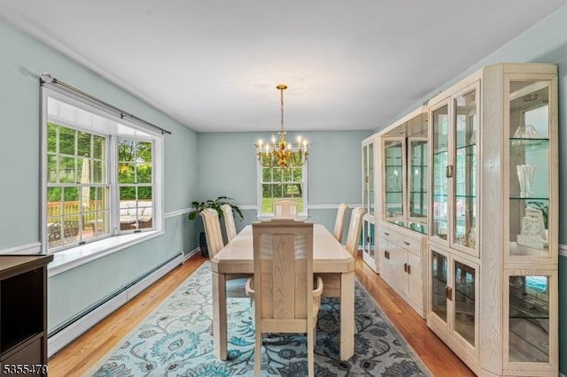 dining space with a baseboard heating unit, a chandelier, and wood finished floors