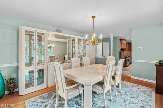 dining space with a chandelier, light wood finished floors, and baseboards
