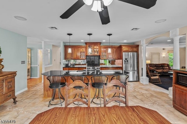 kitchen featuring stainless steel fridge with ice dispenser, decorative columns, a ceiling fan, a kitchen breakfast bar, and recessed lighting
