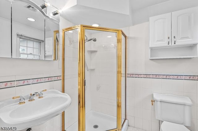 full bath featuring tile walls, a sink, a stall shower, and toilet