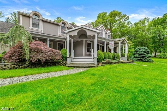 view of front facade featuring covered porch, stucco siding, and a front yard