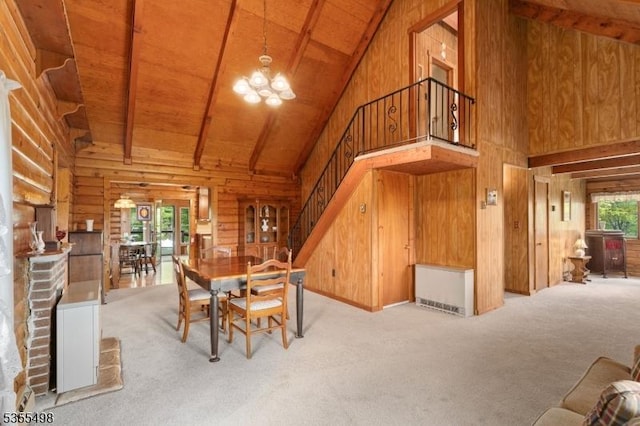 carpeted dining area with high vaulted ceiling, wood ceiling, wooden walls, stairway, and a chandelier
