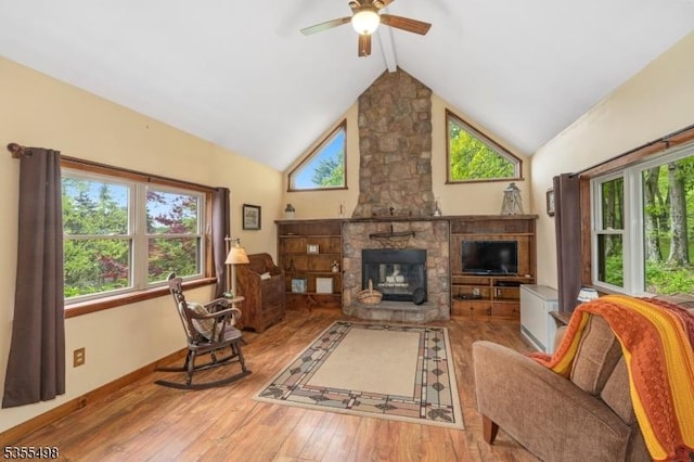 living area featuring a ceiling fan, hardwood / wood-style flooring, a fireplace, and baseboards