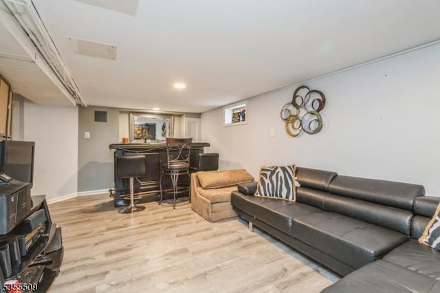 living room with a bar, baseboards, and wood finished floors