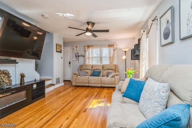 living area featuring visible vents, baseboards, ceiling fan, and wood finished floors