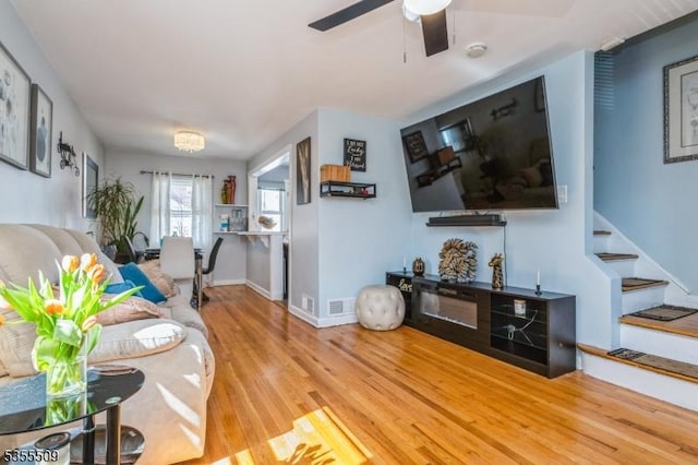 living area with baseboards, stairs, ceiling fan, and wood finished floors