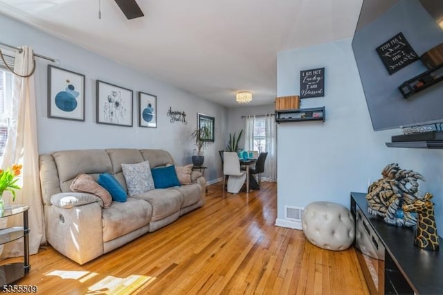 living room with ceiling fan, visible vents, and hardwood / wood-style floors