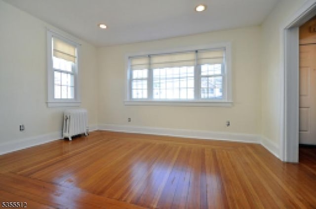 spare room with radiator, wood finished floors, and baseboards