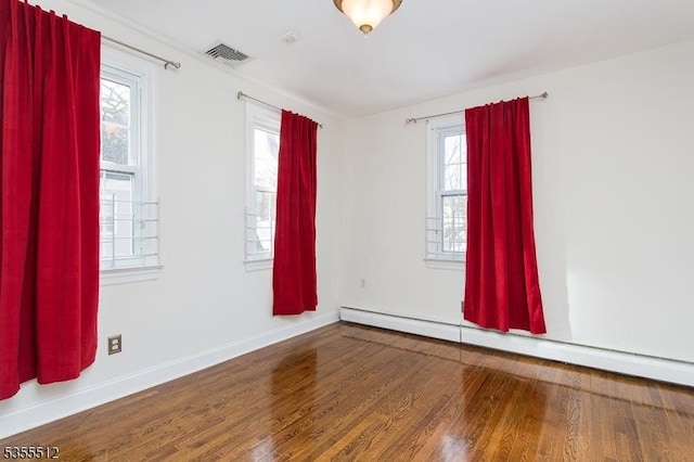 unfurnished room featuring a baseboard radiator, wood finished floors, and baseboards