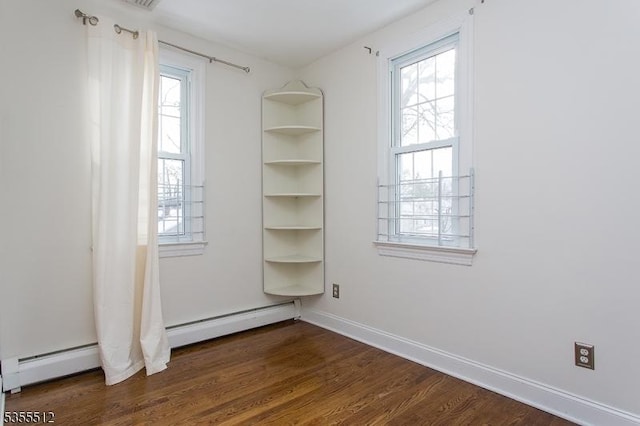 unfurnished bedroom featuring multiple windows, dark wood-type flooring, a baseboard heating unit, and baseboards