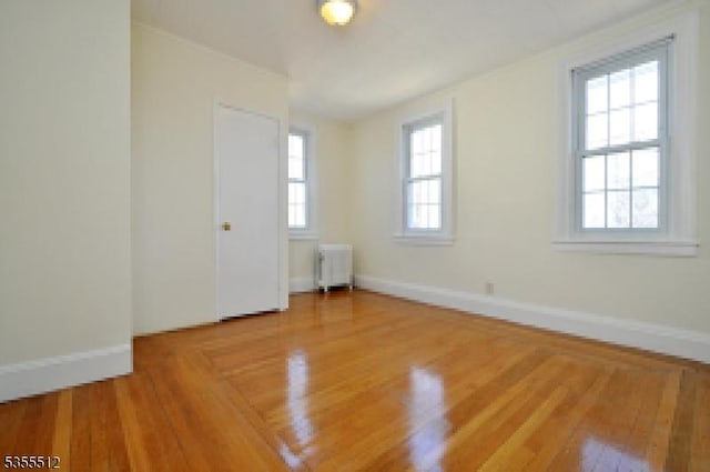 spare room featuring radiator heating unit, wood finished floors, and baseboards