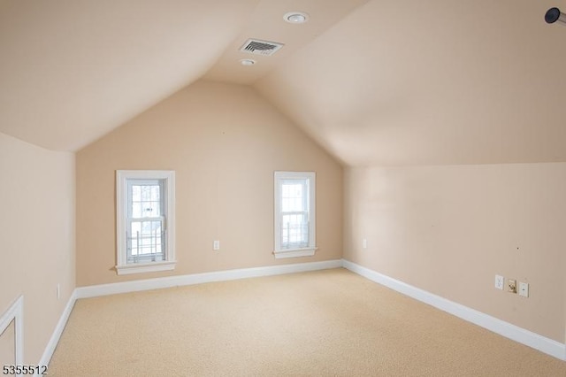 bonus room with lofted ceiling, light colored carpet, baseboards, and plenty of natural light
