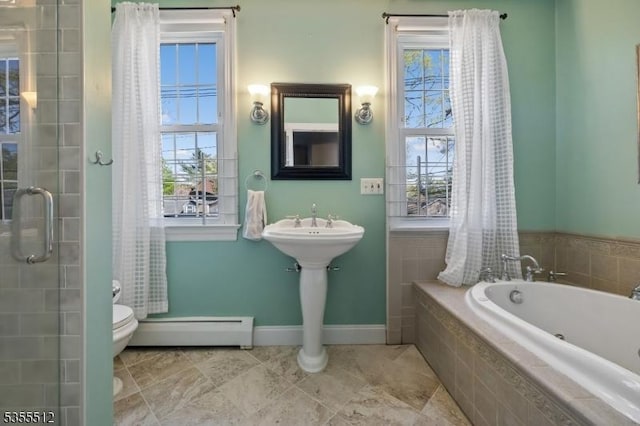 bathroom featuring baseboard heating, plenty of natural light, toilet, and a garden tub