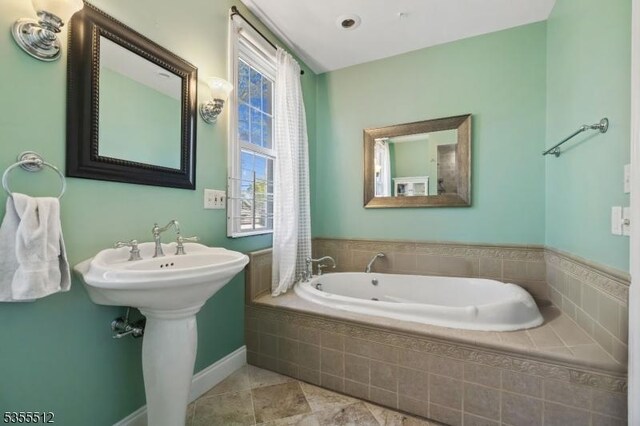 full bath featuring a garden tub and baseboards
