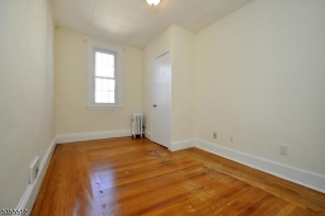 spare room with radiator heating unit, wood finished floors, baseboards, and lofted ceiling