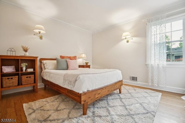 bedroom with crown molding, wood finished floors, and baseboards