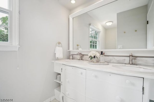 bathroom with double vanity and baseboards