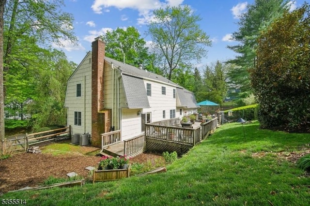 back of house featuring a wooden deck, a chimney, central air condition unit, a shingled roof, and a gambrel roof