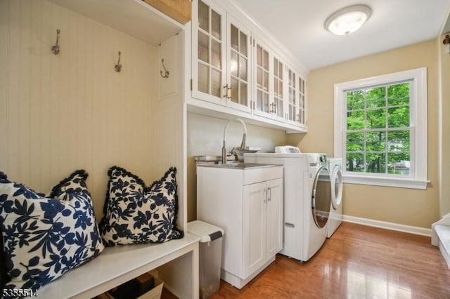 washroom featuring cabinet space, separate washer and dryer, light wood-style floors, and baseboards