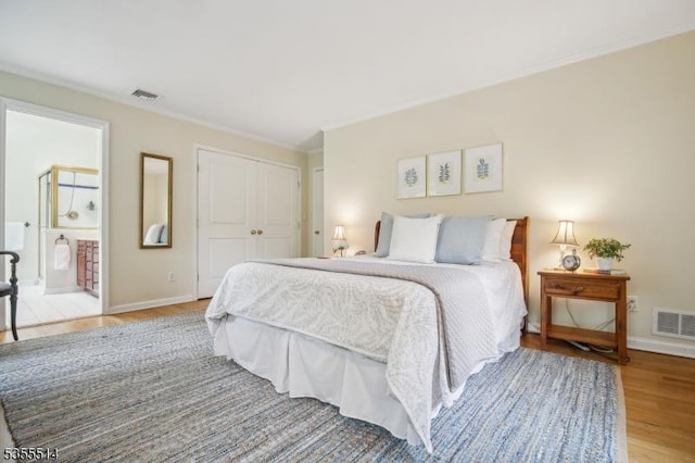 bedroom featuring light wood finished floors, a closet, baseboards, ornamental molding, and ensuite bathroom