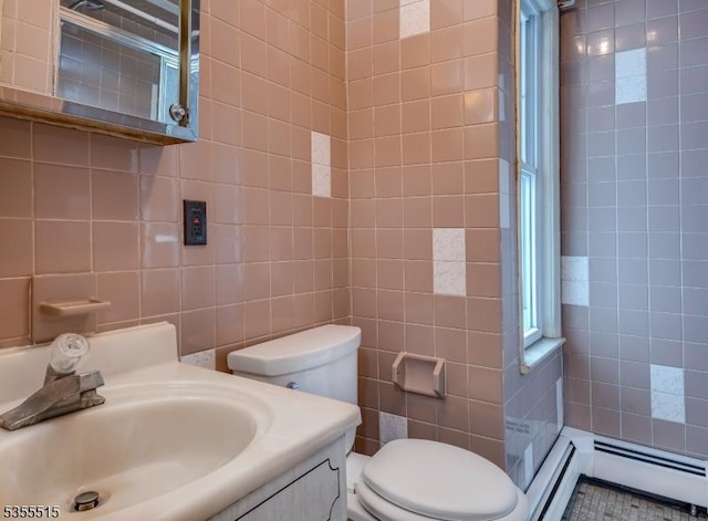 bathroom featuring tile walls, vanity, toilet, and a baseboard heating unit