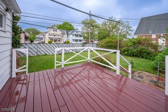 wooden terrace featuring a fenced backyard, a yard, and a residential view