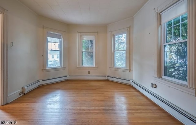 unfurnished room with ornamental molding, baseboard heating, and light wood finished floors