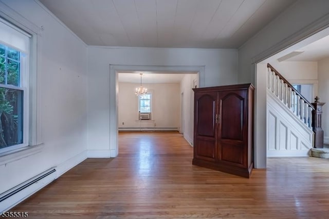 empty room featuring an inviting chandelier, a baseboard radiator, baseboard heating, and light wood finished floors