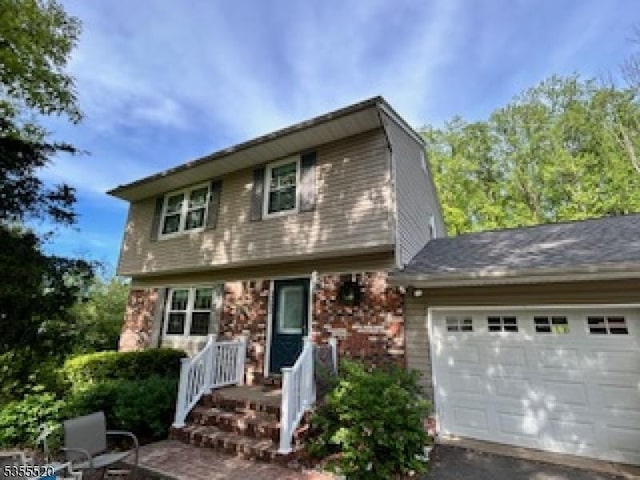 view of front of home featuring a garage, asphalt driveway, and brick siding