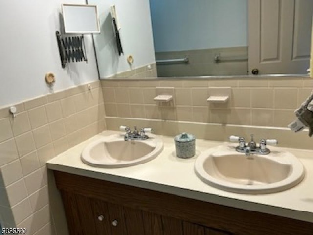 full bath featuring double vanity and tasteful backsplash