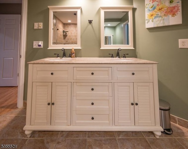 full bathroom featuring baseboards, double vanity, a shower, and tile patterned flooring
